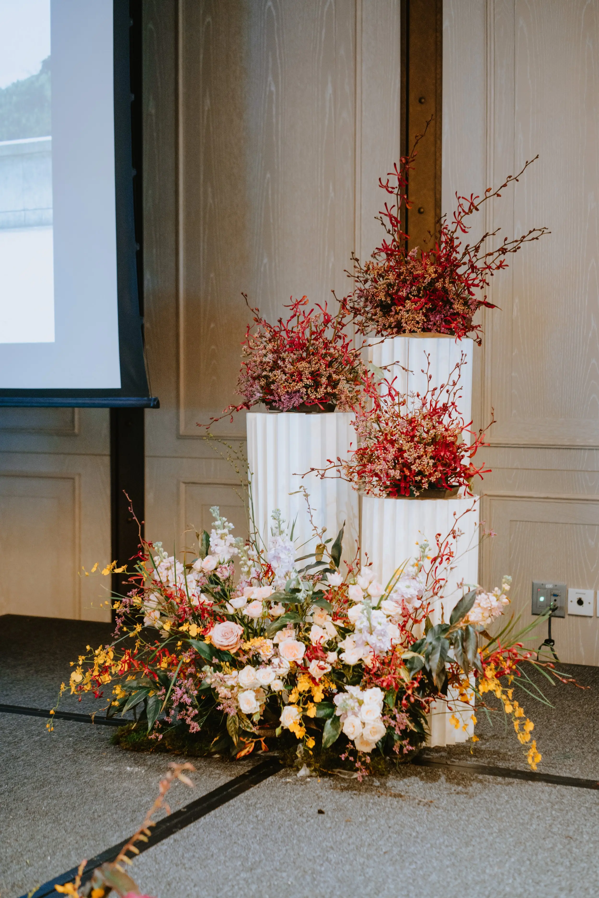 Red themed florals set atop pleated plinths created a key focus of the stage backdrop.