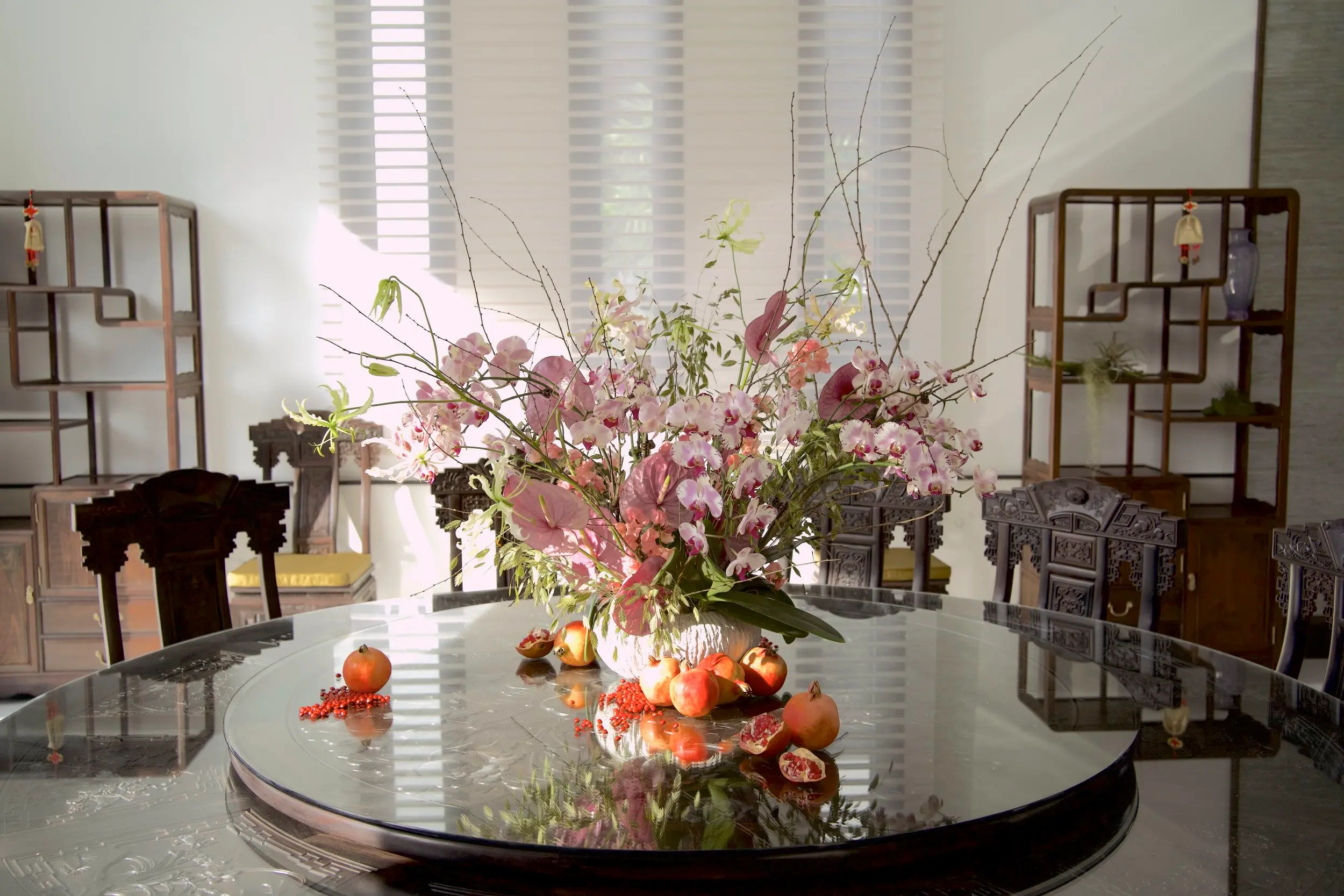 Welcoming the sun’s rays with a burst of purple phalaenopsis orchids and red pomegranates.